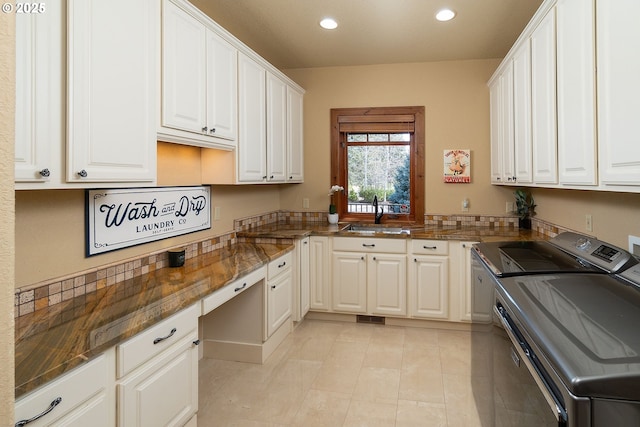 kitchen with recessed lighting, white cabinets, a sink, and separate washer and dryer