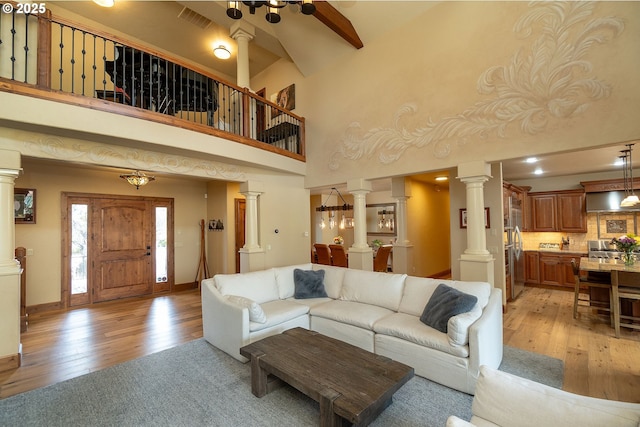 living room featuring decorative columns, visible vents, light wood-style flooring, and baseboards