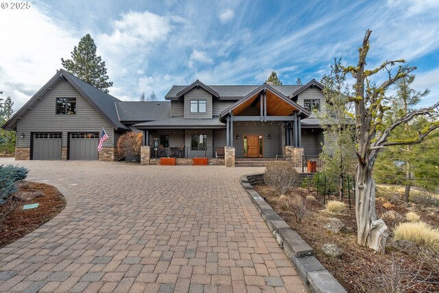 craftsman inspired home featuring covered porch, stone siding, and decorative driveway