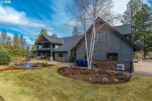 rear view of house featuring ac unit, a yard, a chimney, a patio area, and stone siding