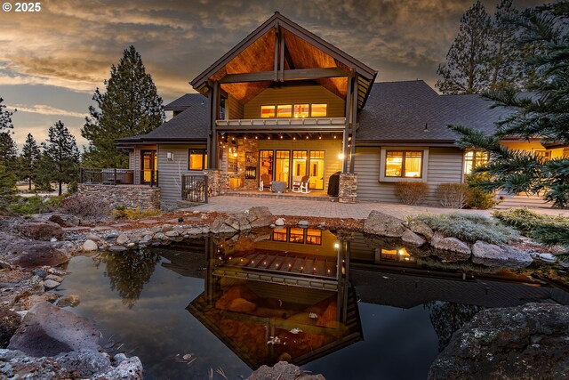 back of property at dusk featuring a shingled roof