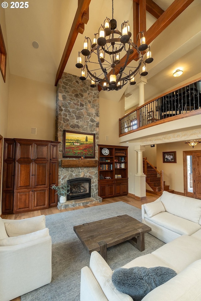 living area featuring a stone fireplace, wood finished floors, high vaulted ceiling, beamed ceiling, and stairs