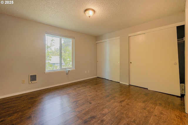 2330 SE Brookwood Ave Unit 222, Hillsboro, OR 97123 - unfurnished bedroom featuring multiple closets, a textured ceiling, wood finished floors, heating unit, and baseboards