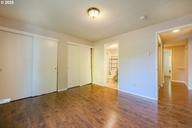 2330 SE Brookwood Ave Unit 222, Hillsboro, OR 97123 - unfurnished bedroom featuring multiple closets, wood finished floors, baseboards, and a textured ceiling