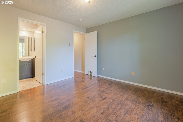 2330 SE Brookwood Ave Unit 222, Hillsboro, OR 97123 - unfurnished bedroom with wood finished floors, baseboards, a textured ceiling, and connected bathroom