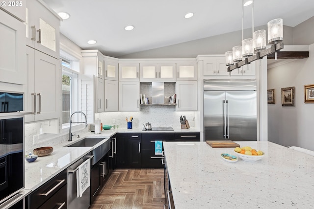 kitchen with white cabinets, decorative backsplash, dark cabinets, stainless steel appliances, and a sink