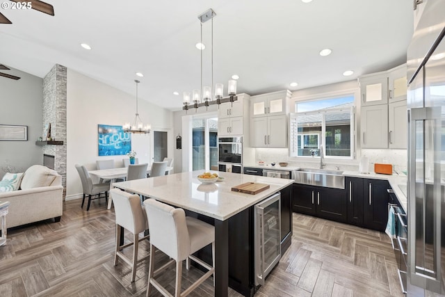 kitchen with lofted ceiling, wine cooler, double wall oven, a sink, and a kitchen breakfast bar