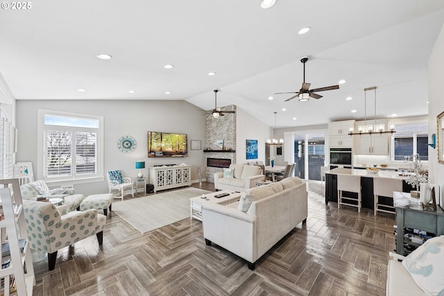 living area with lofted ceiling, recessed lighting, and ceiling fan with notable chandelier