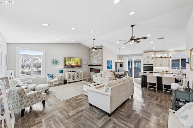 3220 Natalie Way, Bandon, OR 97411 - living room with a ceiling fan, vaulted ceiling, a stone fireplace, a chandelier, and recessed lighting