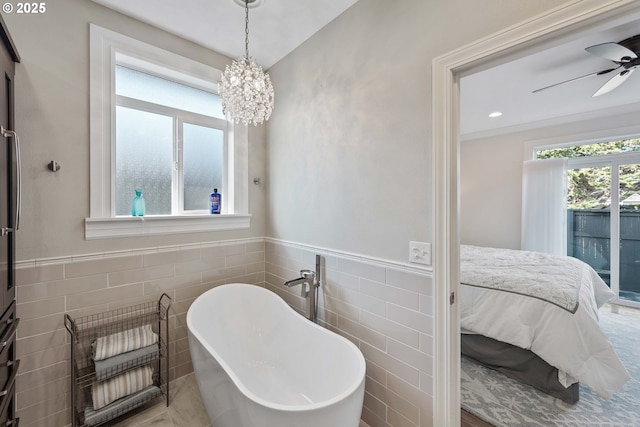 ensuite bathroom with tile walls, a freestanding bath, a ceiling fan, wainscoting, and connected bathroom