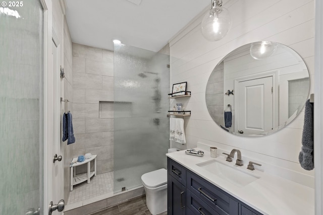 bathroom featuring toilet, walk in shower, wood finished floors, and vanity