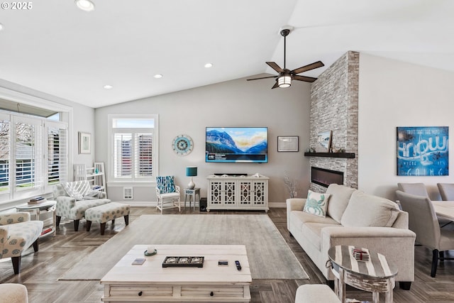 living room featuring lofted ceiling, a stone fireplace, baseboards, and recessed lighting