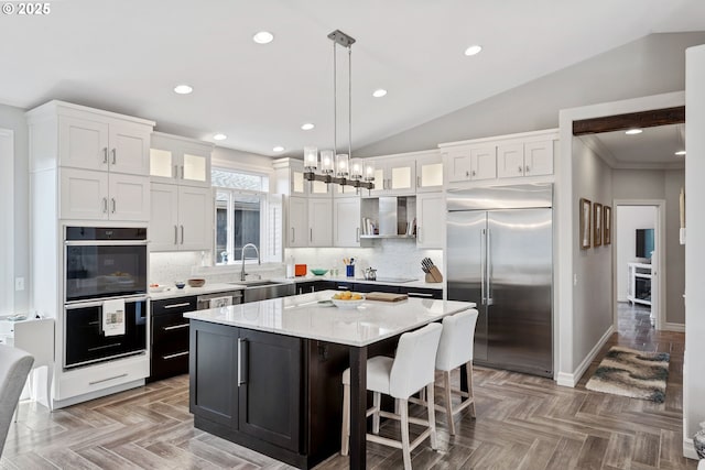 kitchen featuring a center island, white cabinetry, vaulted ceiling, a sink, and black appliances