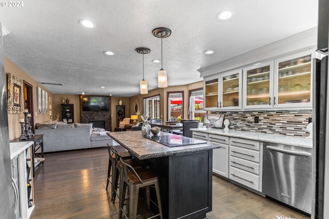 3644 Fall Creek Ct, Keizer, OR 97303 - kitchen with a textured ceiling, a center island, dark wood finished floors, stainless steel dishwasher, and glass insert cabinets