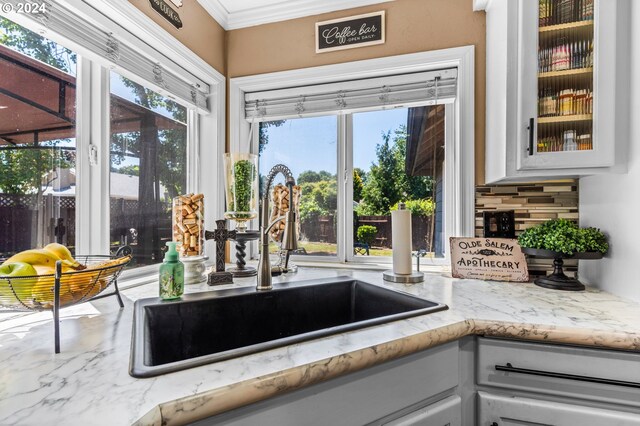 3644 Fall Creek Ct, Keizer, OR 97303 - kitchen with a sink, glass insert cabinets, crown molding, light stone countertops, and tasteful backsplash