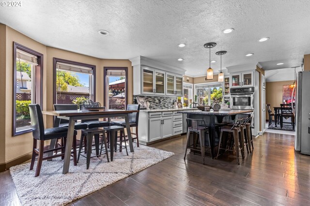 3644 Fall Creek Ct, Keizer, OR 97303 - kitchen with stainless steel appliances, a kitchen island, a textured ceiling, backsplash, and a breakfast bar area