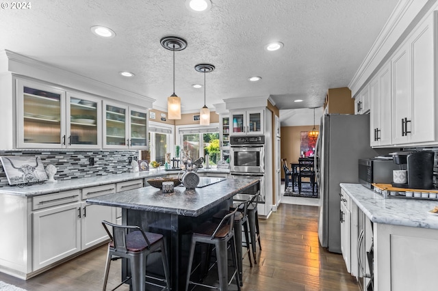 3644 Fall Creek Ct, Keizer, OR 97303 - kitchen featuring a textured ceiling, white cabinetry, a breakfast bar area, tasteful backsplash, and recessed lighting