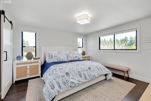 11700 S Makin Ln, Canby, OR 97013 - bedroom featuring a barn door, dark wood-type flooring, and baseboards