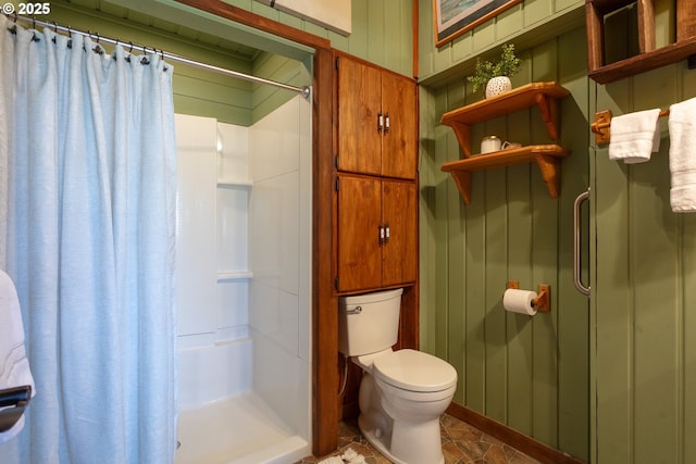 bathroom featuring toilet, a stall shower, and wooden walls