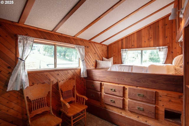 interior space with vaulted ceiling with beams, wooden walls, a textured ceiling, and multiple windows