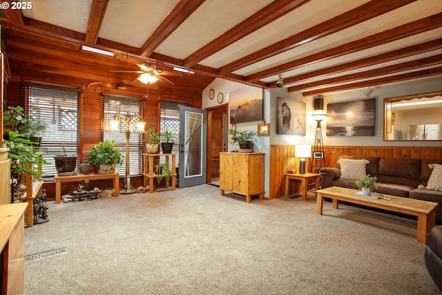 living area with wooden walls, a ceiling fan, wainscoting, carpet, and beam ceiling