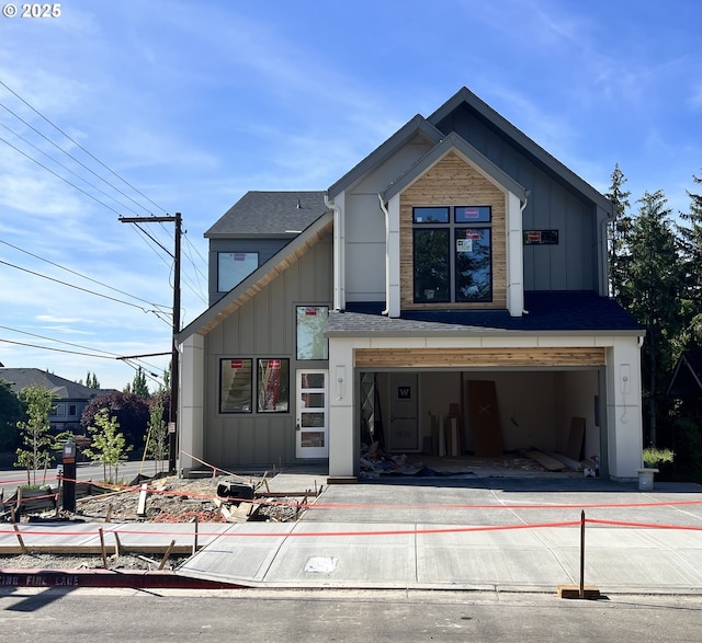 view of front facade with concrete driveway, an attached garage, board and batten siding, and a shingled roof