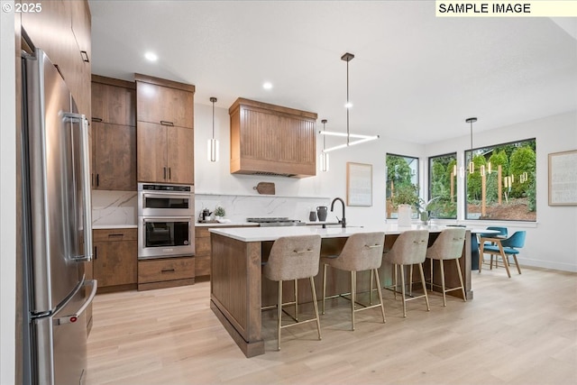 kitchen with stainless steel appliances, light wood-style flooring, light countertops, a kitchen breakfast bar, and recessed lighting