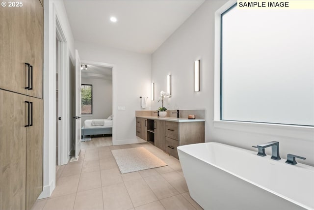 ensuite bathroom featuring a freestanding tub, vanity, tile patterned floors, baseboards, and recessed lighting