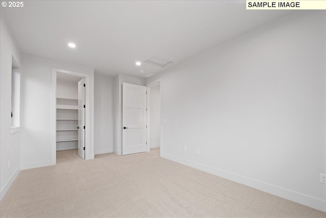 unfurnished bedroom featuring recessed lighting, baseboards, carpet floors, a spacious closet, and attic access