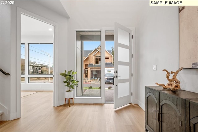 entryway featuring light wood-type flooring, plenty of natural light, and baseboards