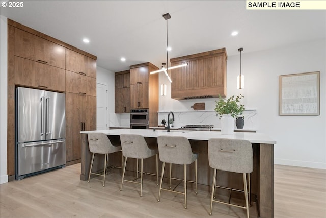 kitchen with appliances with stainless steel finishes, light wood-style flooring, modern cabinets, a breakfast bar area, and recessed lighting