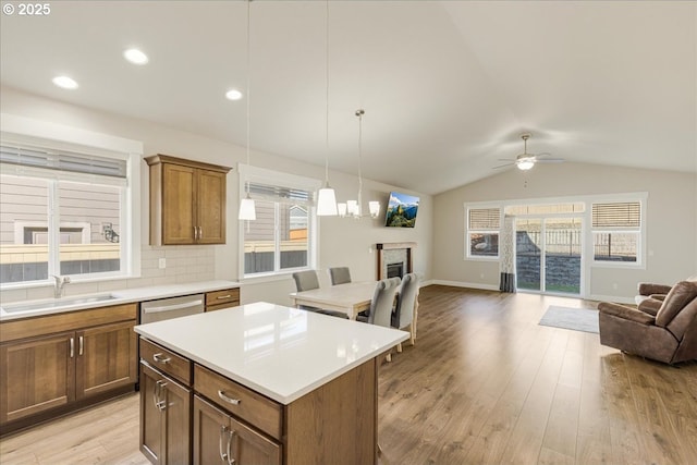 kitchen with lofted ceiling, sink, dishwasher, light hardwood / wood-style floors, and a kitchen island