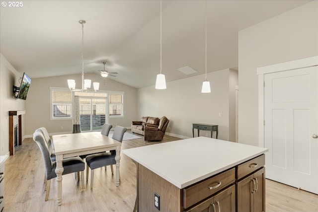 kitchen with lofted ceiling, hanging light fixtures, light hardwood / wood-style flooring, a kitchen island, and ceiling fan with notable chandelier