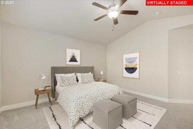 living room with vaulted ceiling, a stone fireplace, ceiling fan, and light wood-type flooring