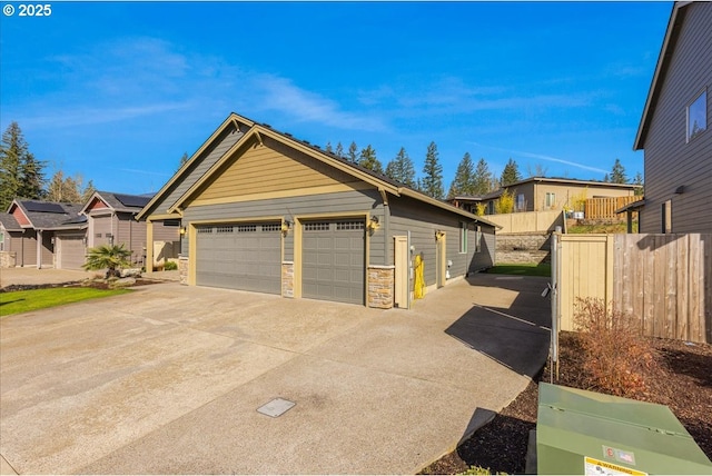 exterior space featuring a garage, a residential view, stone siding, and fence