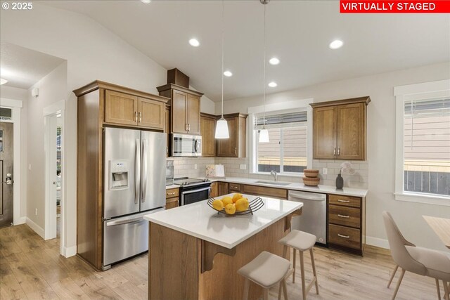 kitchen with stainless steel appliances, sink, backsplash, and decorative light fixtures