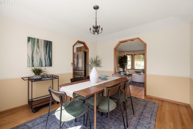 8156 SW 159th Pl, Beaverton, OR 97007 - dining space featuring arched walkways, light wood finished floors, a chandelier, and baseboards
