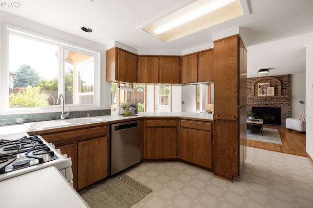 8156 SW 159th Pl, Beaverton, OR 97007 - kitchen with stainless steel dishwasher, light countertops, brown cabinets, a fireplace, and a sink