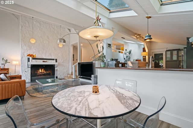 1115 Lake Front Rd, Lake Oswego, OR 97034 - dining space featuring a skylight, wood finished floors, a fireplace, and vaulted ceiling