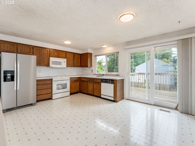 20621 SW Martinazzi Ave, Tualatin, OR 97062 - kitchen with white appliances, a textured ceiling, light countertops, brown cabinets, and a sink