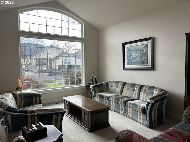 living room with a healthy amount of sunlight, vaulted ceiling, and light carpet