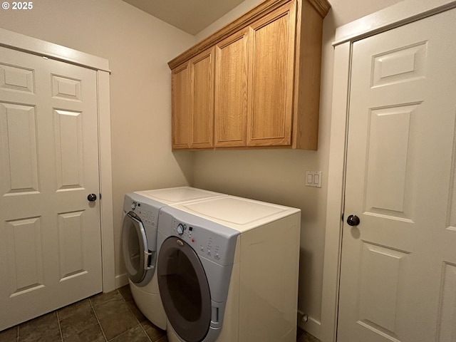 laundry area featuring cabinets, dark tile patterned flooring, and washing machine and clothes dryer