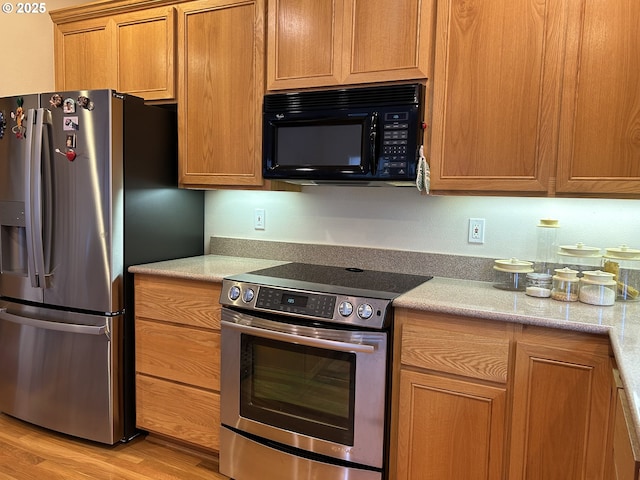 kitchen with appliances with stainless steel finishes and light hardwood / wood-style flooring