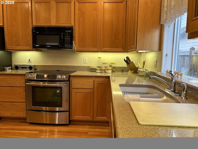 kitchen featuring stainless steel electric stove, sink, and hardwood / wood-style floors