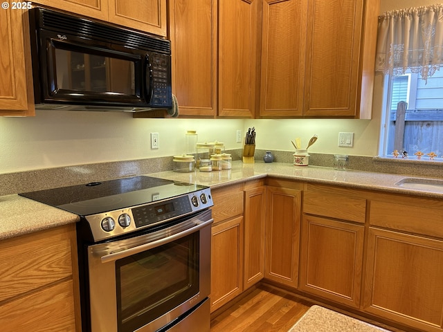 kitchen with sink, light hardwood / wood-style flooring, and stainless steel range with electric stovetop