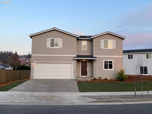 traditional home with a front yard, driveway, an attached garage, and fence