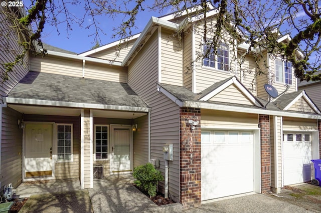 multi unit property with a garage, a shingled roof, a porch, and brick siding