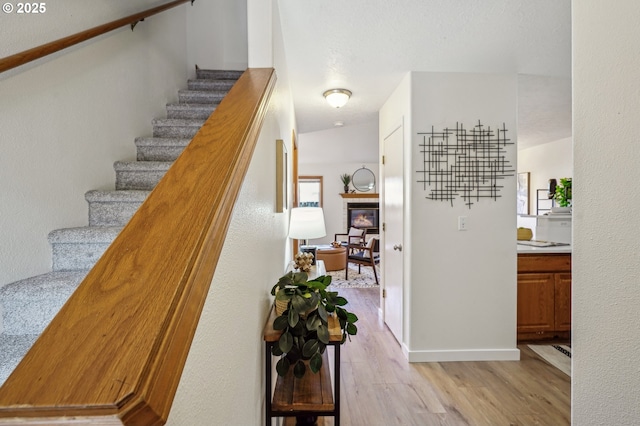 stairway featuring a tiled fireplace and wood finished floors