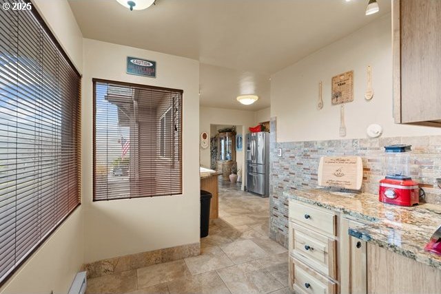 kitchen featuring light stone counters, stainless steel refrigerator, and light brown cabinets