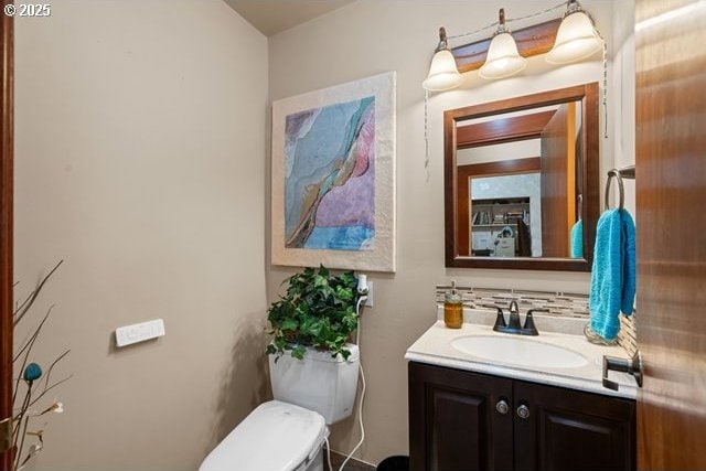 bathroom featuring tasteful backsplash, vanity, and toilet